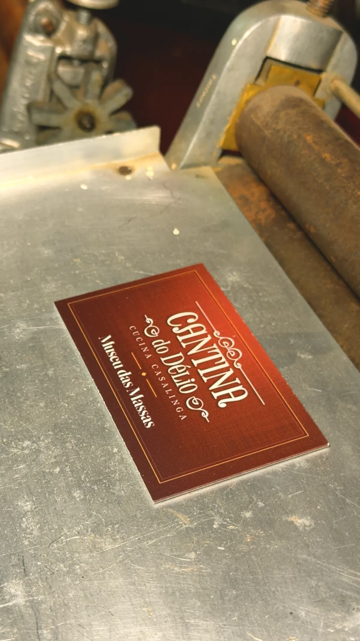 Placa vermelha do Museu das Massas sobre uma máquina de massa antiga