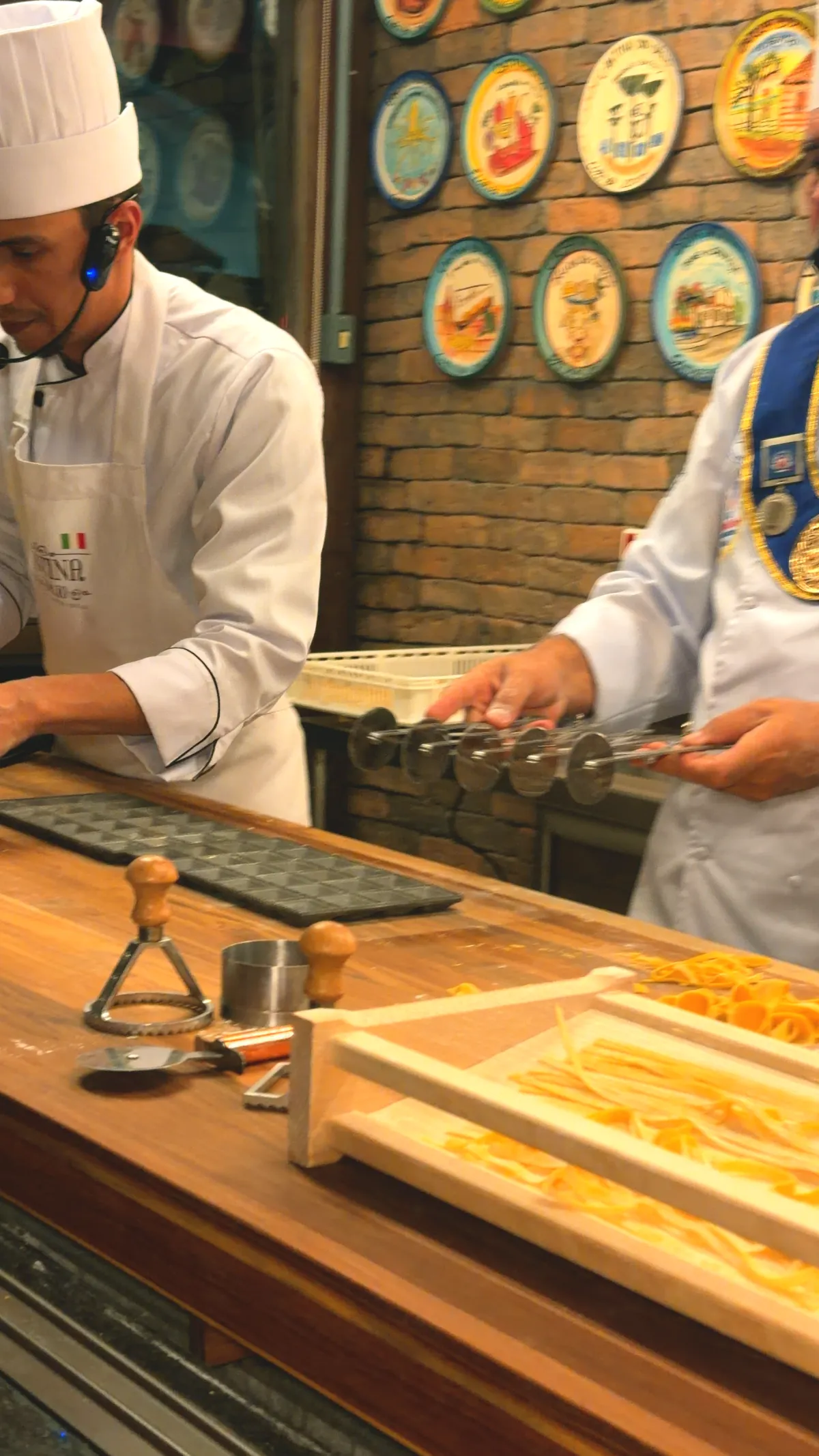 Dois cozinheiros de chapéu de chef trabalhando a massa na bancada