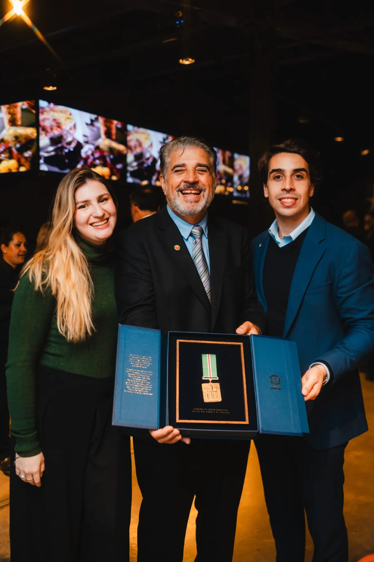 Sabrina Baruf, Délio e César Canabrava segurando a comenda aberta