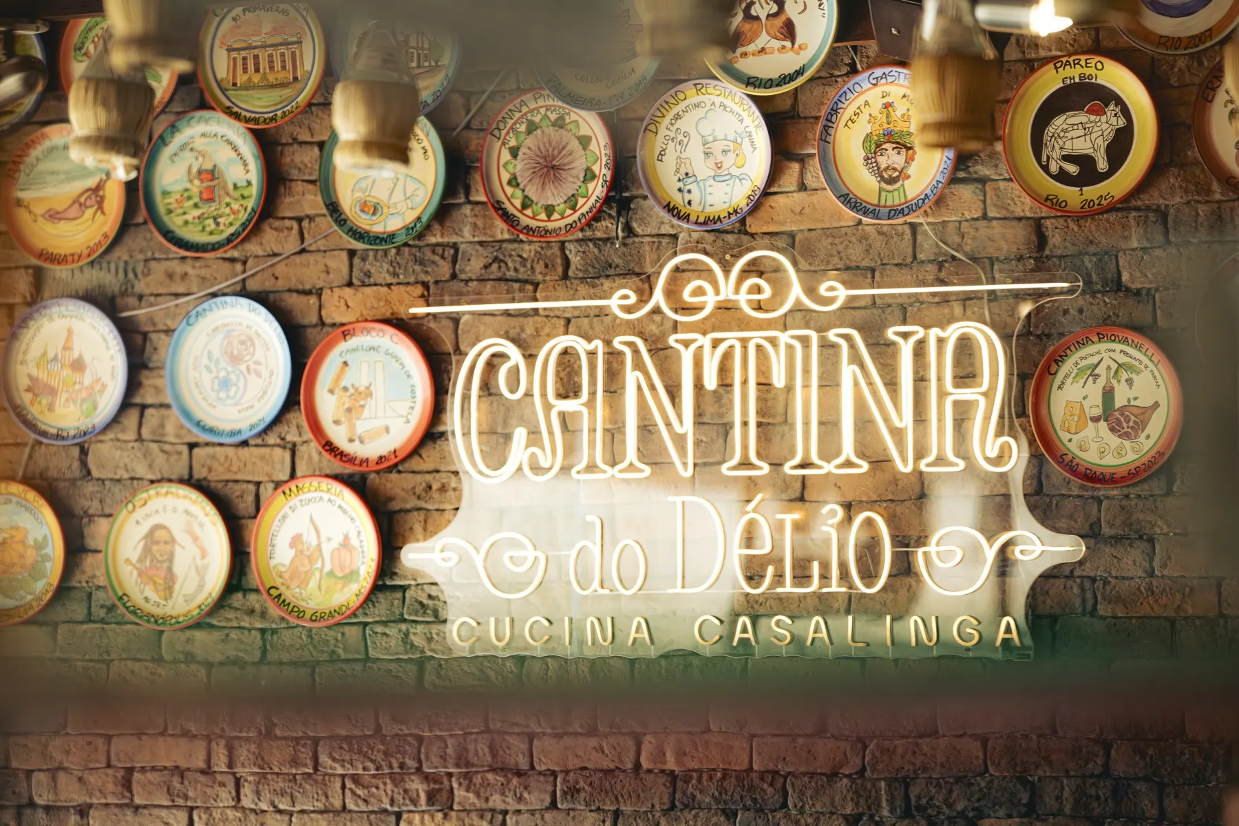 Letreiro neon da Cantina na parede de pratos pintados