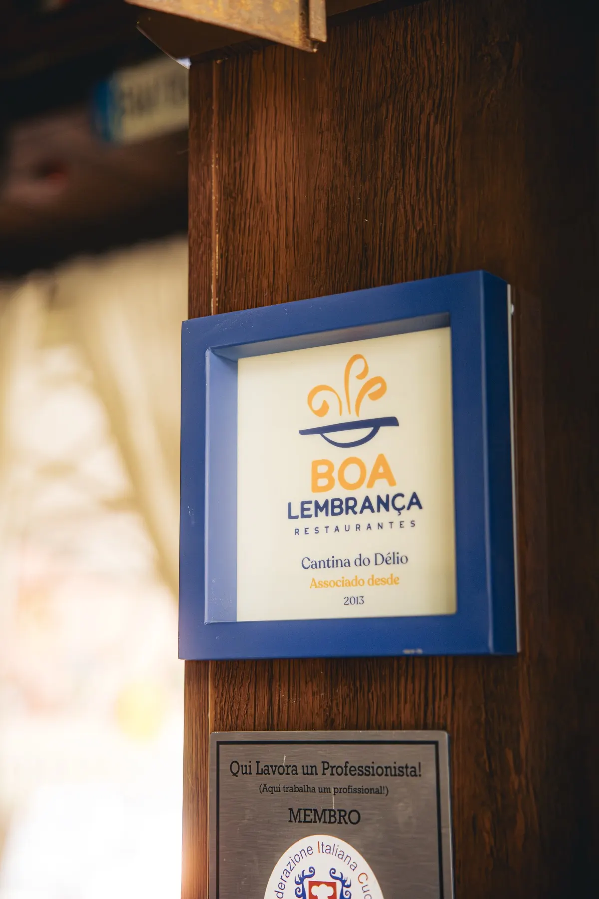 Placa da associação Boa Lembrança na parede da Cantina